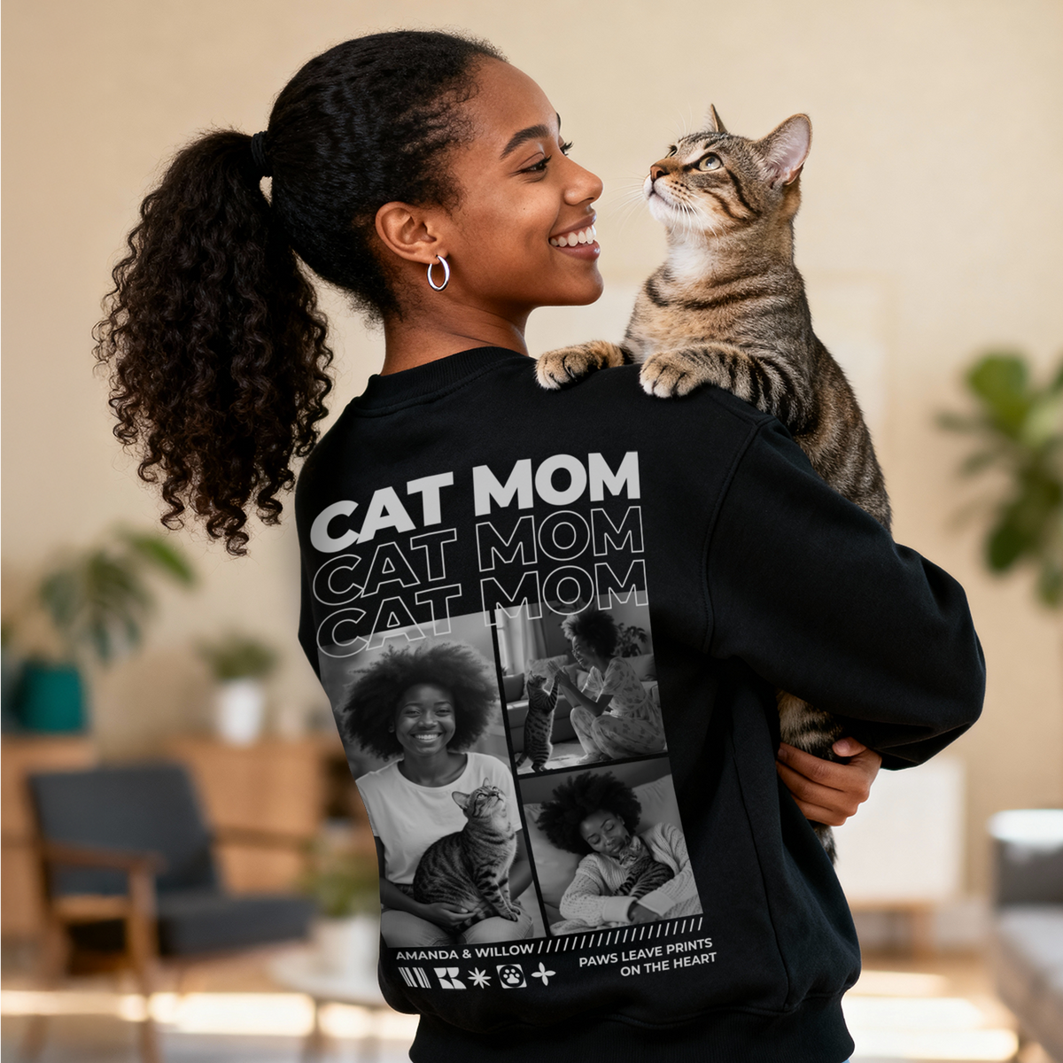 Woman holding a tabby cat in a black Cat Mom sweater