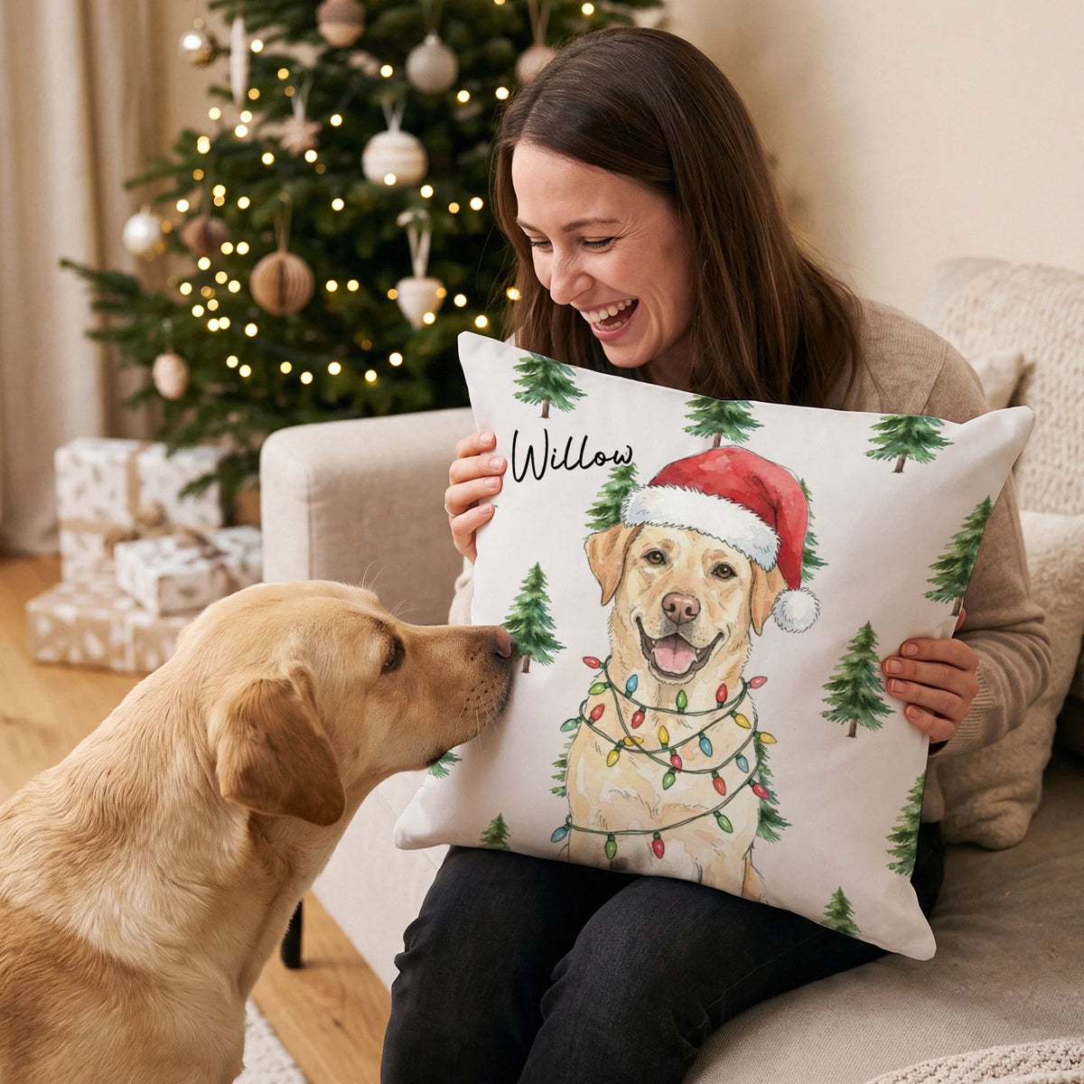 Woman on the sofa holding a pillow with a watercolor Labrador in a Santa hat next to her dog