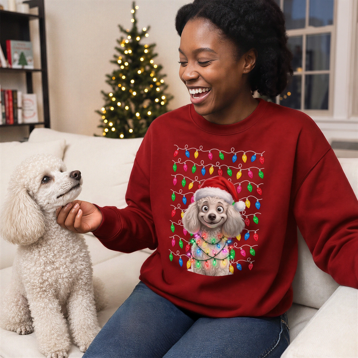 Woman in a red Christmas sweater with a cartoon of her white poodle by the Christmas tree