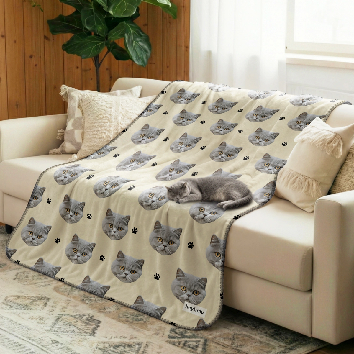 Gray cat curled up on the sofa on a cream Cat Photo blanket with paw prints