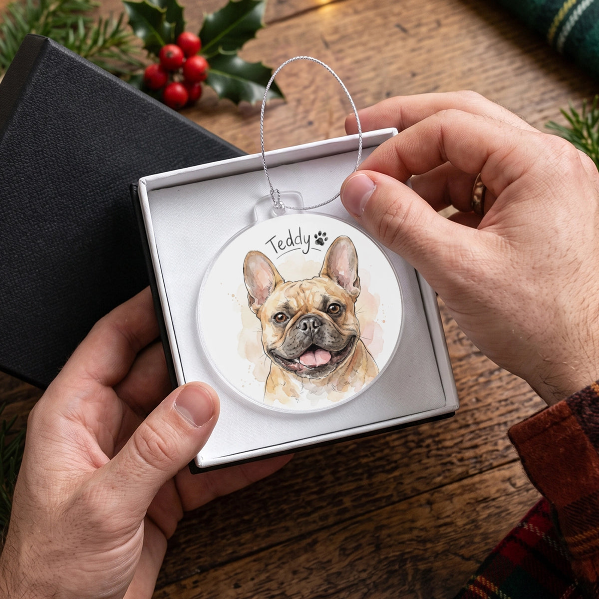 Hands holding the French Bulldog ornament with the name Teddy in an open gift box