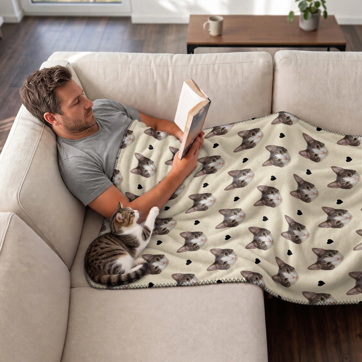 Man reading on the couch under the Cat Photo blanket with his tabby cat