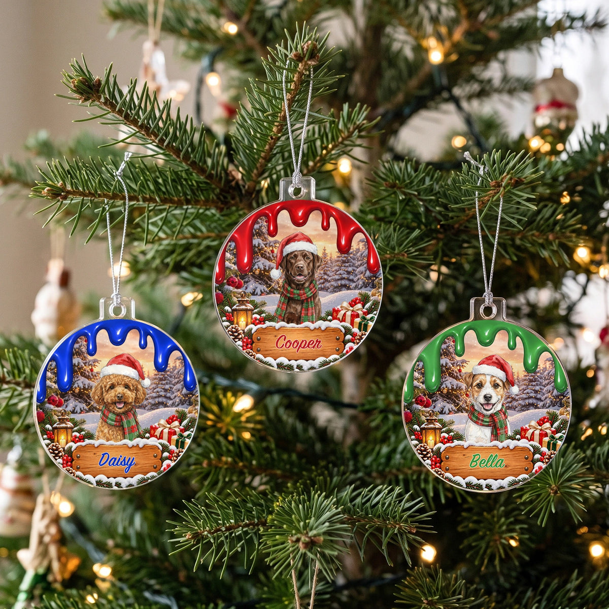 Three ornaments in blue, red and green with dogs named Daisy, Cooper and Bella on the Christmas tree